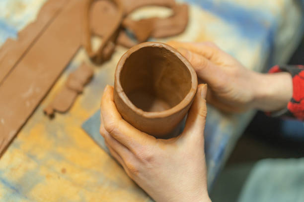 istock Close up of human hands making a clay mug. Pottery teaching class. Potter makes dishes from clay, ceramics. 1473957715