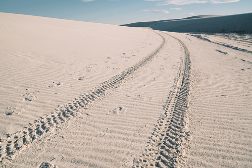 From above of trace of wheels on sand in White Sands National Park against blue cloudy sky in sunny day