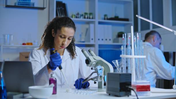 istock Cosmetic laboratory worker taking cosmetic sample to examine under microscope 1473960547