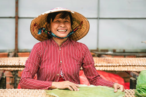 portrait of smiling vietnamese woman holding rice noodle plate in manufacture