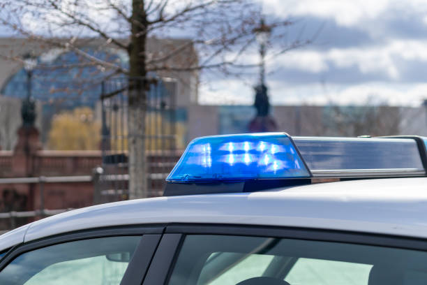 istock Police Car With Blue Flash Light Against Building 1473963603
