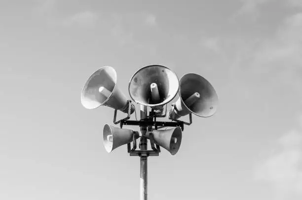 5 grayscale megaphones on a pole against the sky