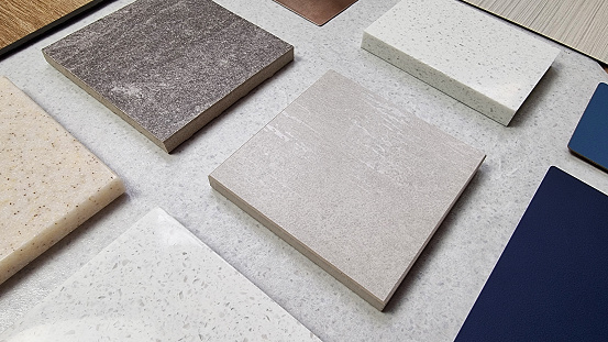 samples of interior stone material consists travertine tile, rustic concrete tile, grainy artificial stones, quartz with blue laminated. close up perspective view of selected materials on board.