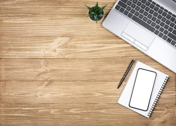 istock Smartphone with blank screen, laptop, notepad and green plant on wooden background 1473974577