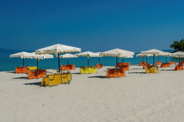 Folded colorful sea beds below sun umbrellas on an empty sandy beach in Chalkidiki Peninsula, Greece. stock photo
