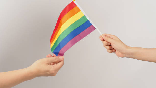istock Two hands send and receive a rainbow flag on white background. LGBT CONCEPT. 1473977167