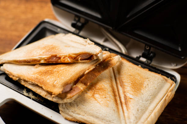 istock Freshly made toasted sandwiches in a sandwich maker on a wooden background. Toasted triangular sandwiches with cheese. 1473977663