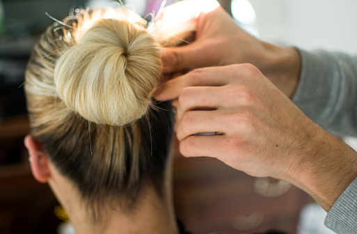 Hairdresser stabs hair with hairpin