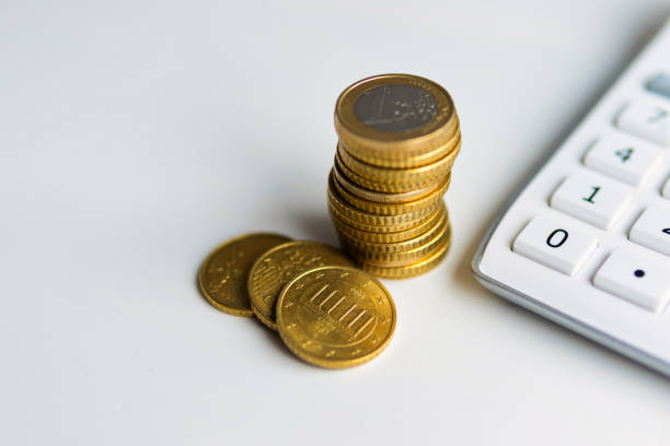 istock Coins and calculator on white desktop 1473981314