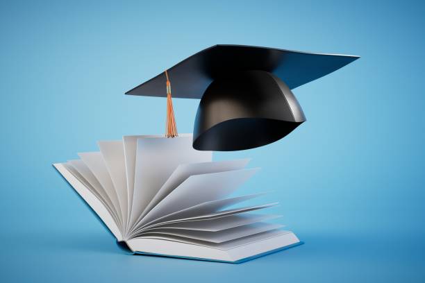 istock obtaining higher education. an open book and a master's cap on a blue background. 3D render 1473982702