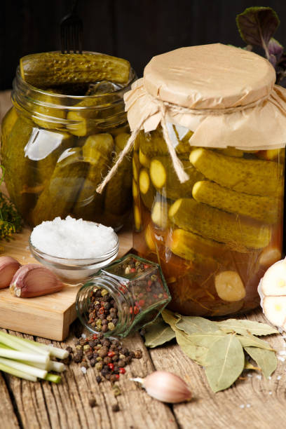 istock Pickled cucumbers in a jars on a dark wooden background. 1473987091