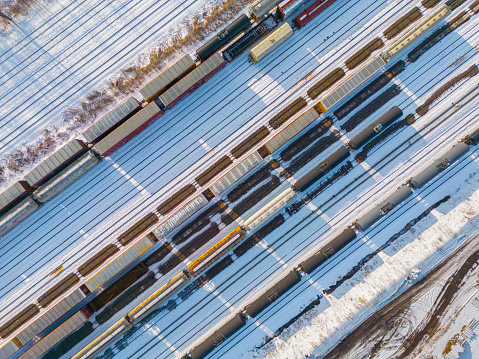 Aerial view of freight trains in snowy rail yard. Among the trains are places where other trains were parked, which left eerie shadow-like marks in the snow.