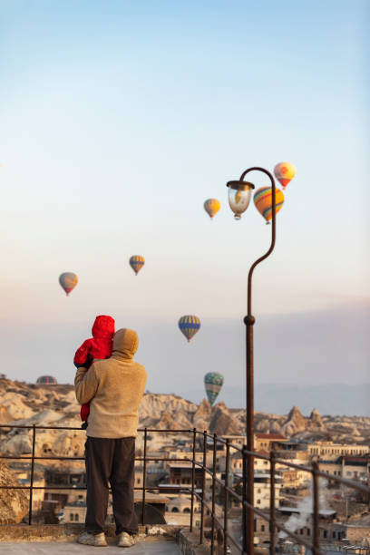 padre con il figlio che guarda le mongolfiere in cappadocia - balloon moving up child flying foto e immagini stock