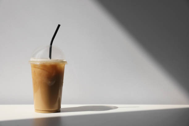 istock Plastic takeaway cup of delicious iced coffee on white table under sunlight, space for text 1473988623