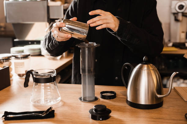 istock Barista pour ground coffee over aeropress before pouring water from drip kettle. Process of brewing aeropress coffee in cafe. 1473989623