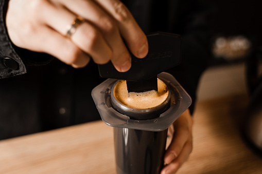 Close-up barista brews Aeropress coffee and stirs it inside. Process of aeropress alternative method brewing coffee