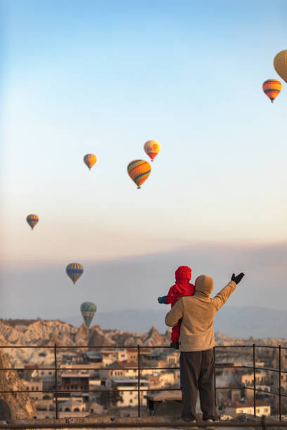 padre con il figlio che guarda le mongolfiere in cappadocia - balloon moving up child flying foto e immagini stock