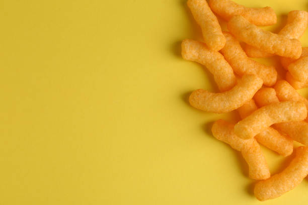 istock Tasty cheesy corn puffs on yellow background, flat lay. Space for text 1473990135