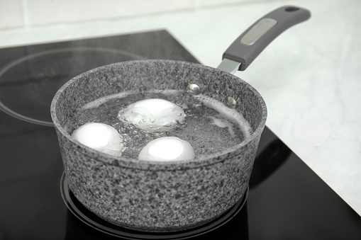 Boiling chicken eggs in saucepan on electric stove