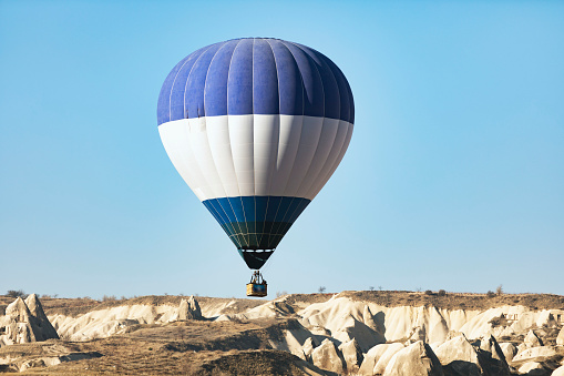 Hot air balloon flying over mountains in Cappadocia