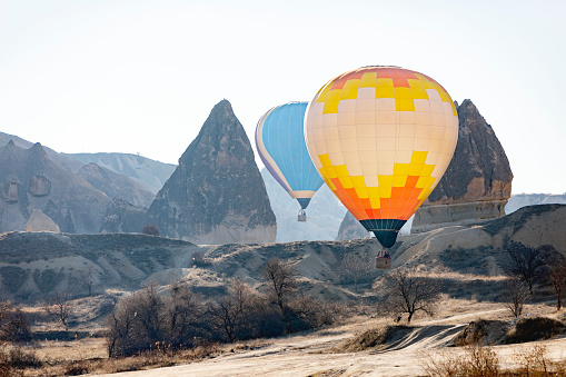 Hot air balloons flying over mountains in Cappadocia