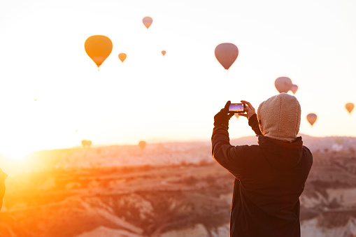 Adult man making photo of air hot balloons in Cappadocia on mobile