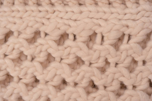 istock A fragment of beige knitted fabric, knitted from white sheep wool. 1473991276
