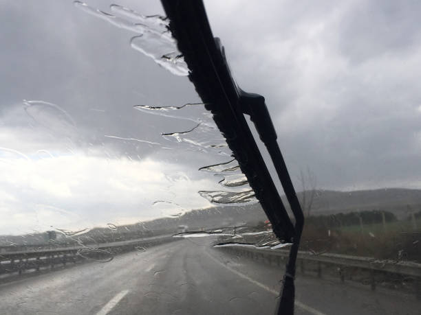 istock Driving on rainy day. Windshield wiper with rain and road 1473991695