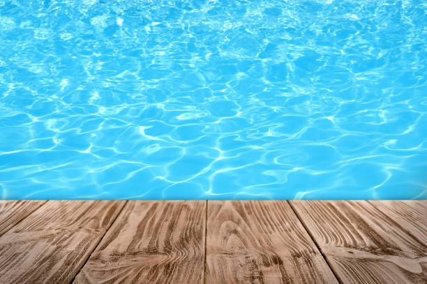 istock Empty wooden surface near swimming pool with clear water. Space for design 1473992664