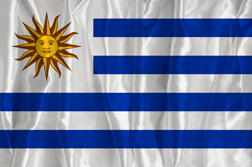 The flag of Uruguay on a silk background is a great national symbol. Texture of fabrics The official state symbol of the country
