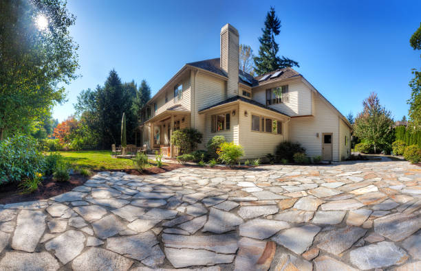 Vernon, British Columbia, Canada- May 13,2025: Driveway into a hilltop bungalow. White wooden slat fence with white and brown toned rocks along side
