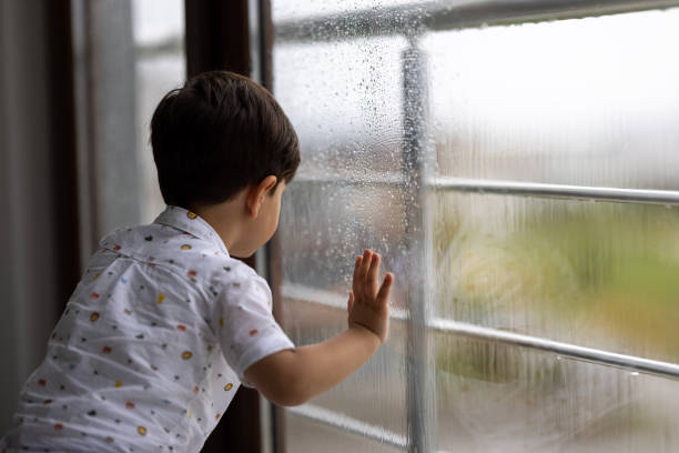 istock Little boy watching the rain through the window 1473998669