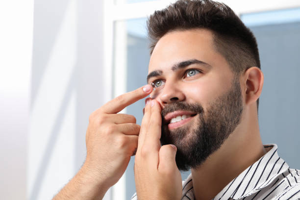 istock Young man putting in contact lens indoors 1473998776