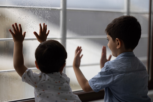 Little boy watching the rain through the window