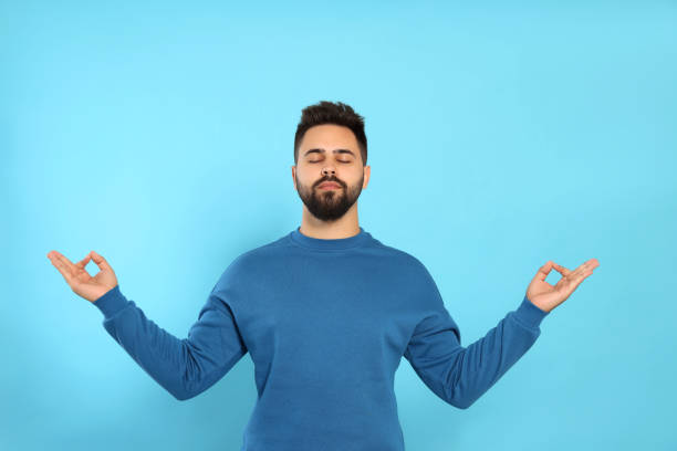 istock Young man meditating on light blue background. Zen concept 1473998823