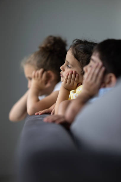 Little children watching the rain through the window