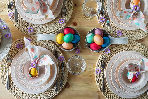Easter table setting with painted eggs, Easter cake and cutlery on the festive table