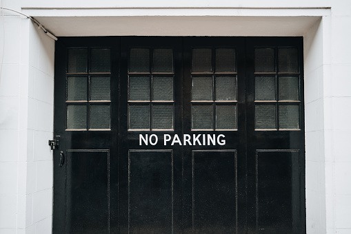 No parking sign on a black wooden garage door of a house in London, UK.