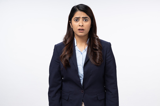 Portrait of curious frustrated young businesswoman looking at camera on white background