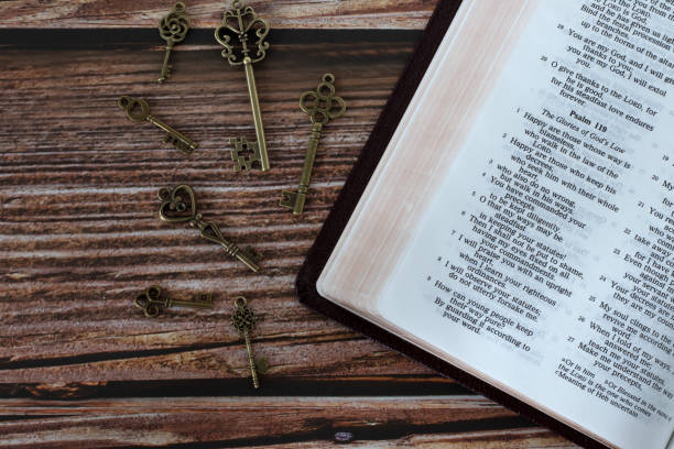 istock Ancient keys and open holy bible book on wooden table, top view 1474004478