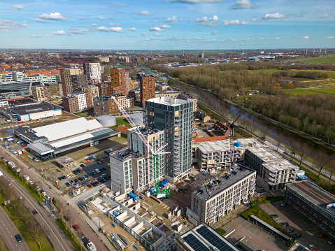 This photo was taken by a drone. It shows a construction site with operating cranes. They are building new apartment buildings in the city of Leiden.