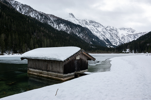 A snowy wooden shed in winter on the Jagersee lake in Austria. Snowy winter mountains in the Alps.