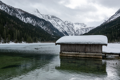 A snowy wooden shed in winter on the Jagersee lake in Austria. Snowy winter mountains in the Alps.