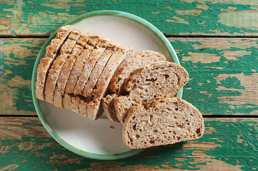 Closeup shot of an unrecognisable woman spreading butter on a slice of toasted bread at home