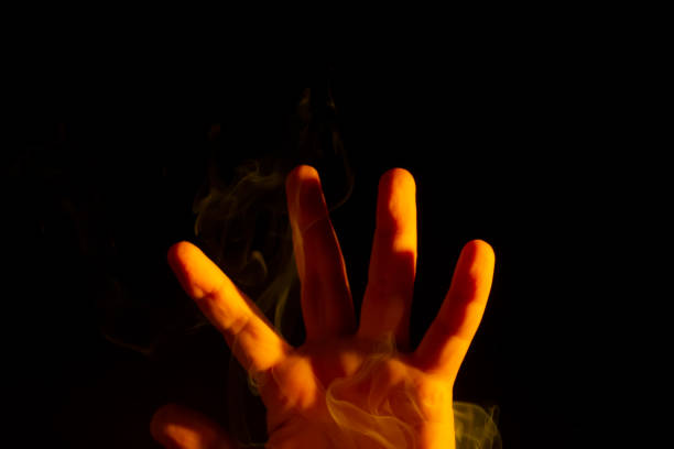 istock A male hand lit yellow with smoke around it 1474013432