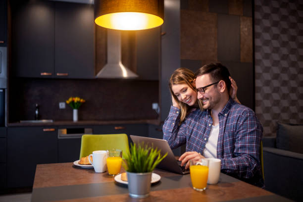 istock Couple having breakfast and using laptop in modern kitchen 1474014324