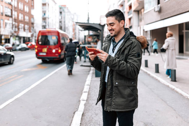 istock Man using his phone at the bus station 1474015679