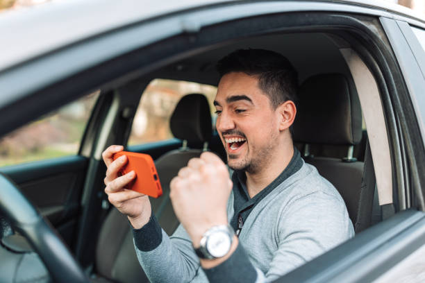 istock Man cheering and watching a video in his car 1474015733