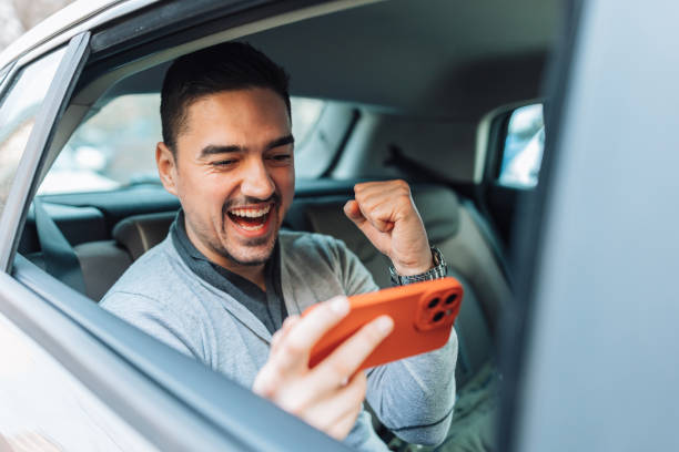 istock Man in a car cheering and watching a video 1474015781