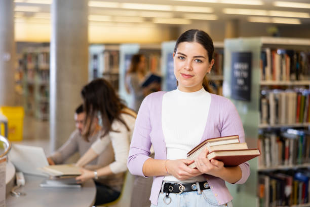 istock Successful female student standing with books in library 1474017306